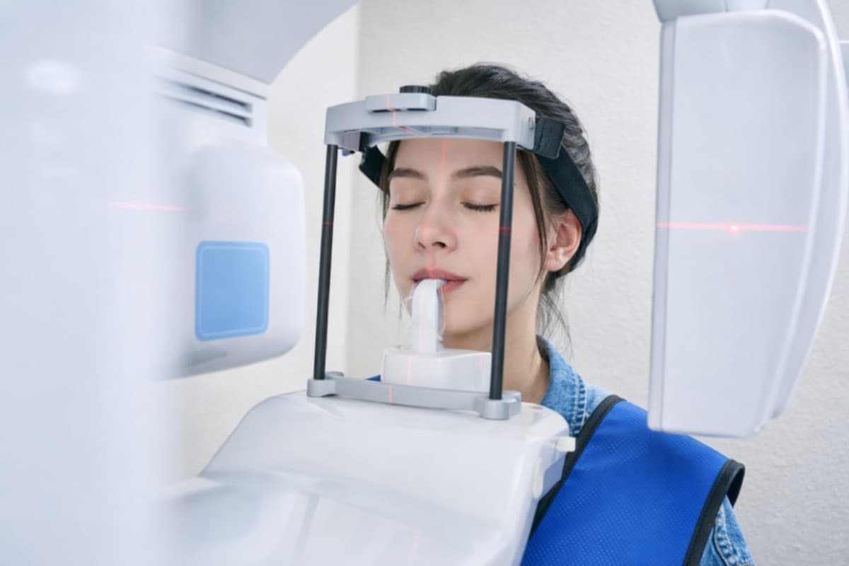 Tomografie CBCT 3D dentară Bacău — pacientă tânără în aparatul de radiografie panoramică digitală cu ghidare laser, instrument esențial pentru diagnosticul precis înainte de tratamentul de canal la Chromatic Dental Clinic