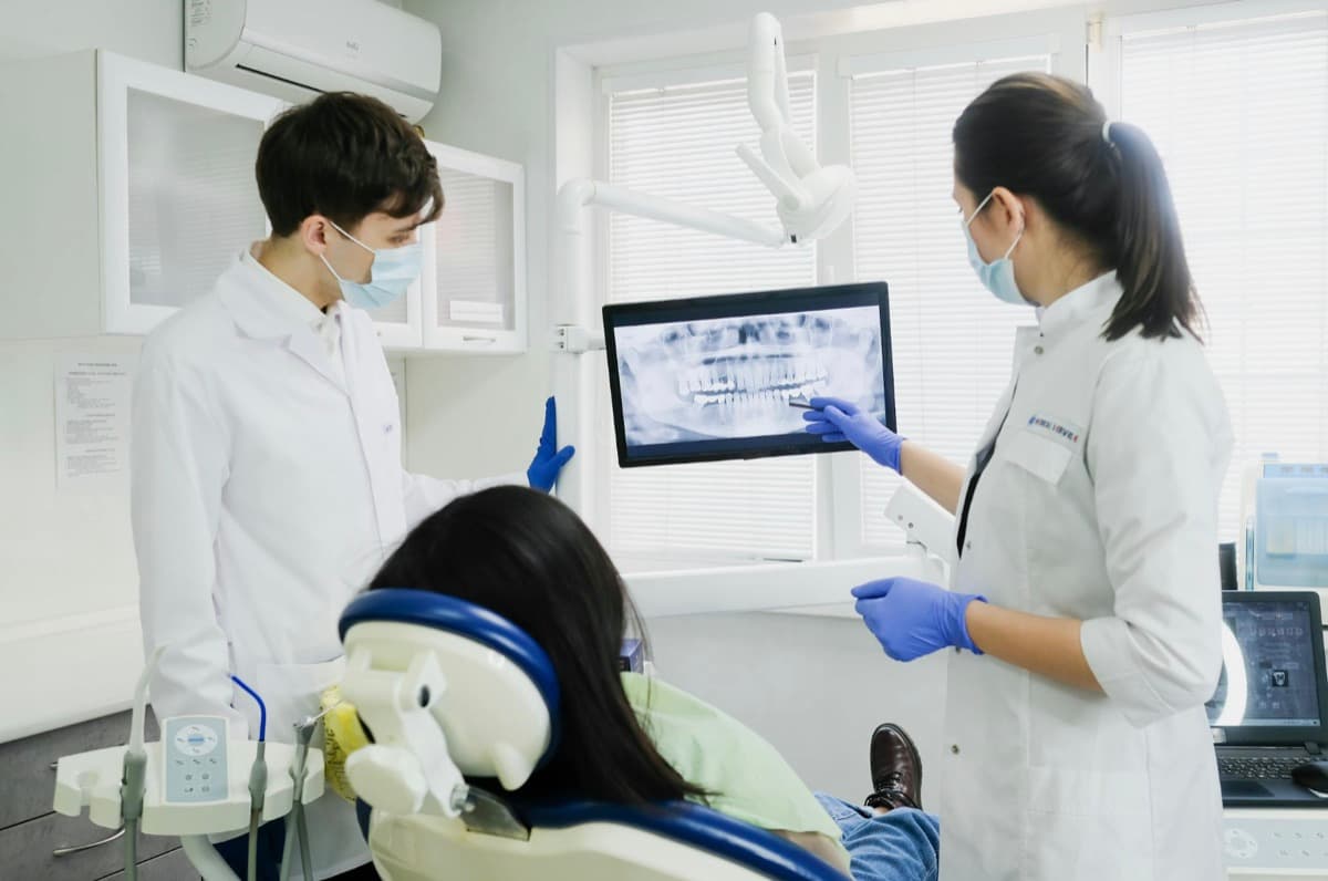 Dentist Bacău — medici stomatologi analizează radiografia panoramică digitală a pacientei pentru diagnostic și planificarea refacerii zâmbetului la Chromatic Dental Clinic