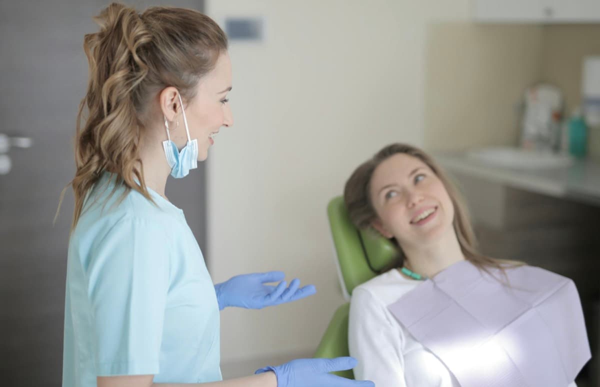 De ce ne este frică de dentist Bacău — medic stomatolog explică zâmbind pacientei procedura, pacientă relaxată în scaunul stomatologic la Chromatic Dental Clinic, atmosferă caldă fără frică