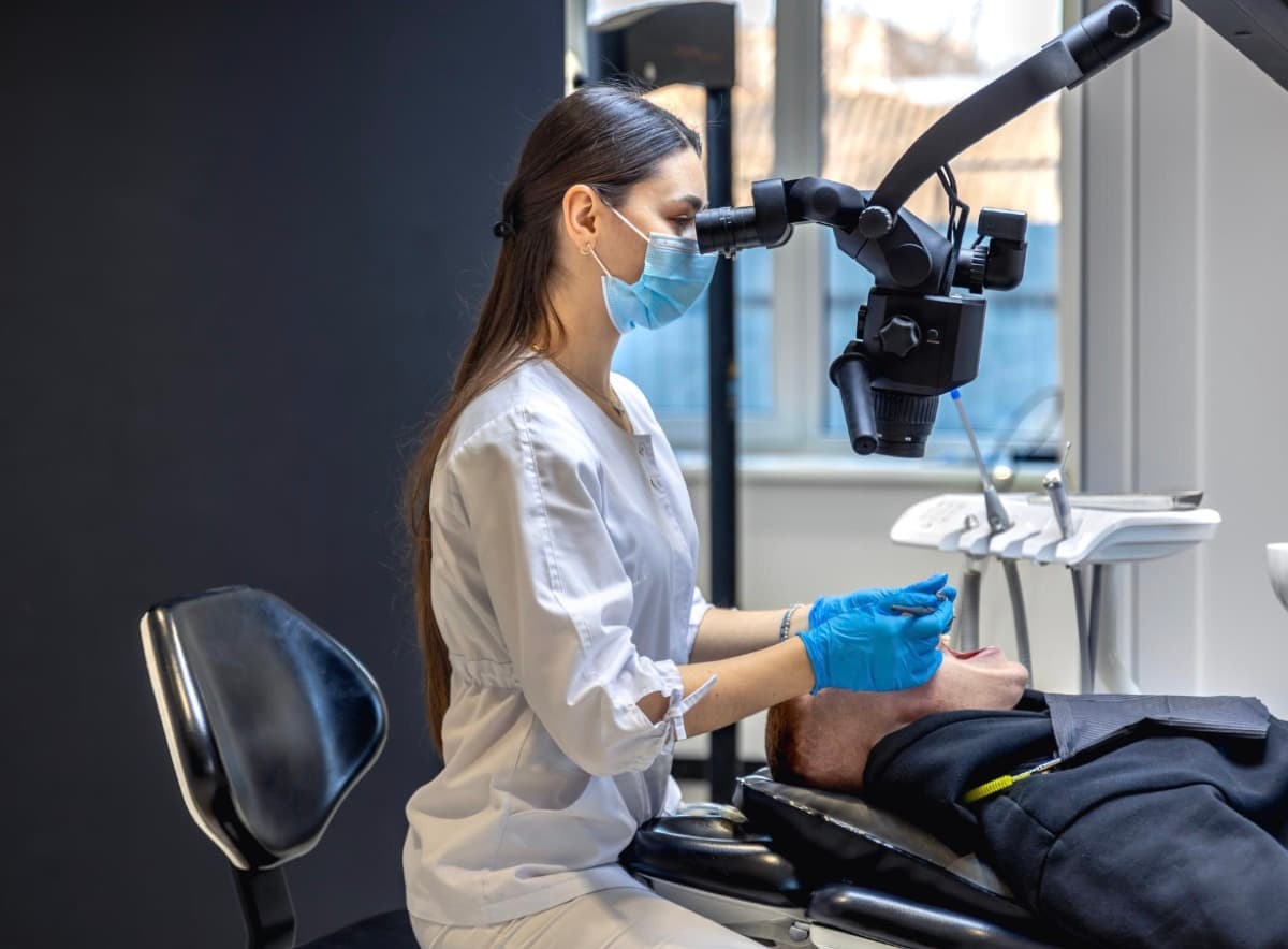 Microscop dentar Bacău — medic stomatolog tratează un pacient cu microscop dentar pentru precizie maximă la Chromatic Dental Clinic