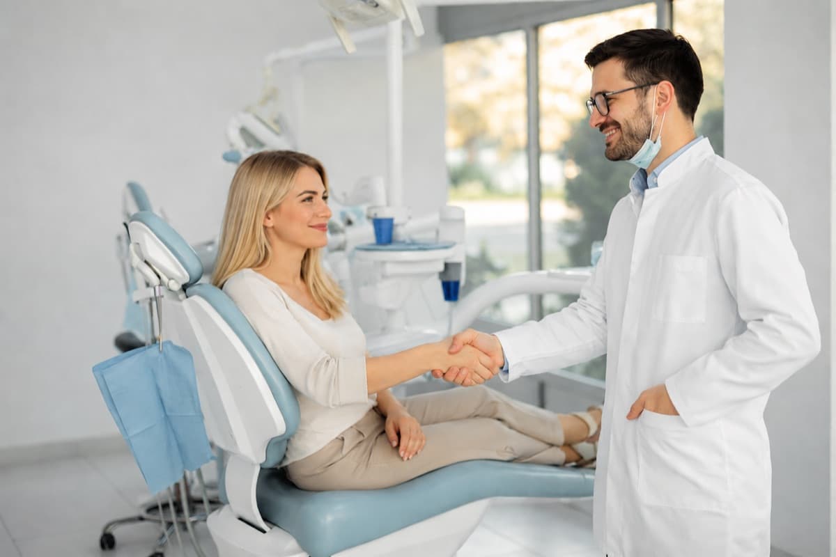 Programare tratament de canal Bacău — pacientă zâmbitoare dă mâna cu medicul stomatolog la finalul consultației, începutul unei relații de încredere pentru salvarea dintelui la Chromatic Dental Clinic