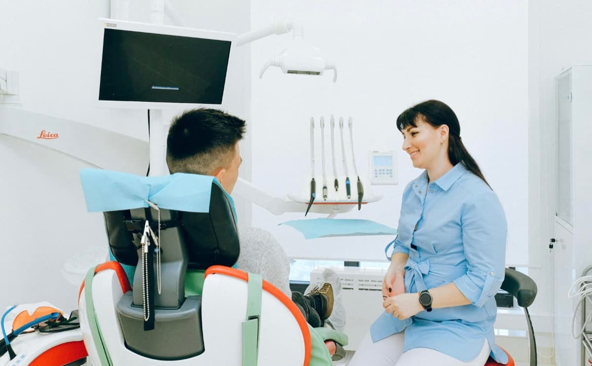 Dentist bun pentru pacienți anxioși Bacău — medic stomatolog Chromatic Dental Clinic discută calm cu pacientul în scaunul stomatologic, atmosferă relaxată, comunicare răbdătoare