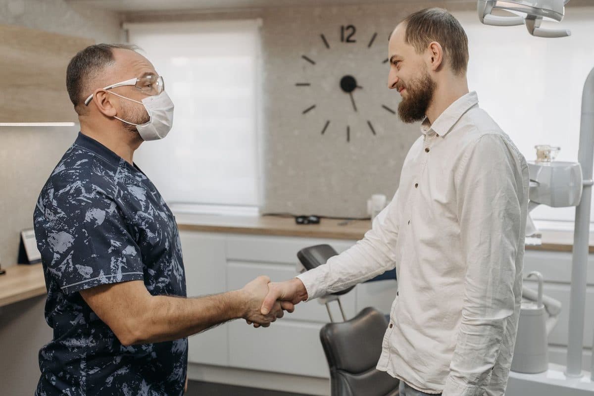 Pacient care dă mâna cu medicul după ce a ales plata în rate pentru implantul dentar, la clinica din Bacău