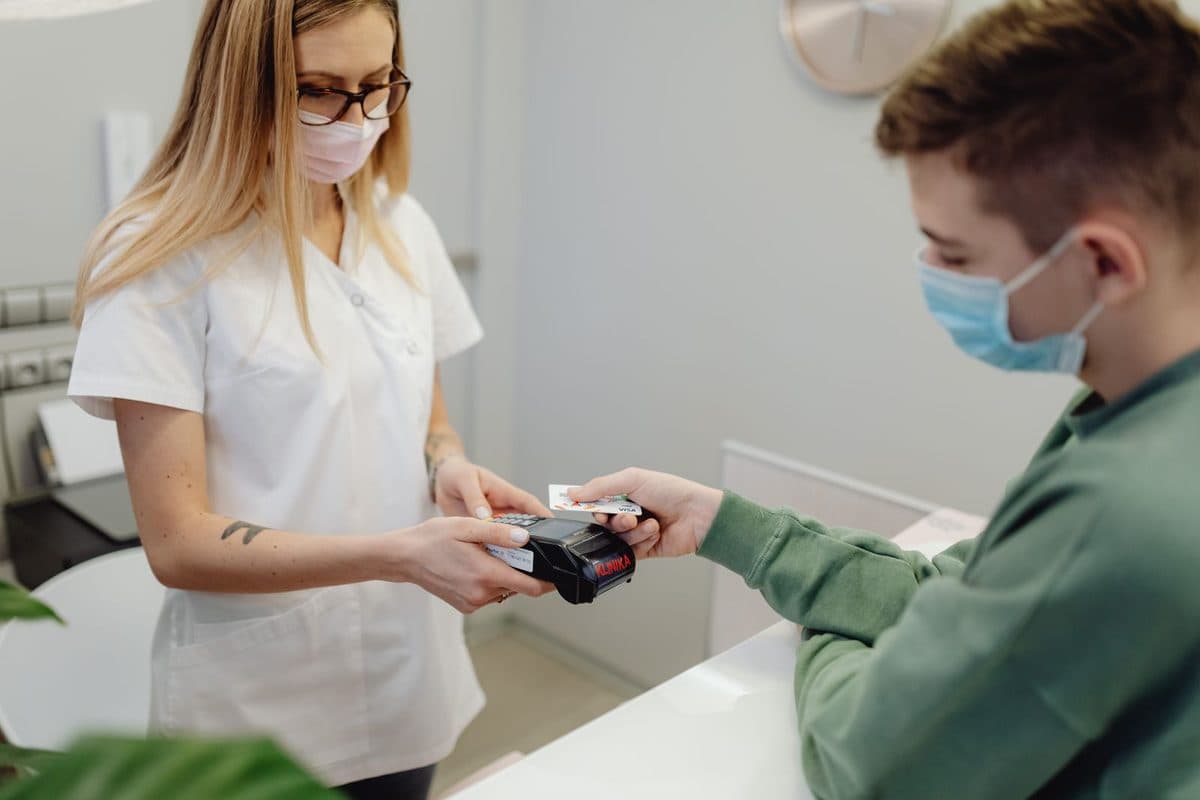 Pacient care achită la recepție o etapă a tratamentului cu implant dentar plătit în rate, la clinica din Bacău