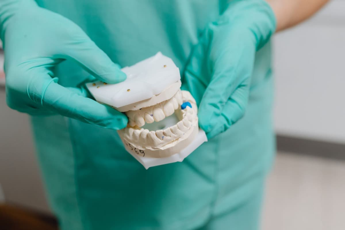 Medic verificând macheta pentru o coroană dentară la clinica din Bacău