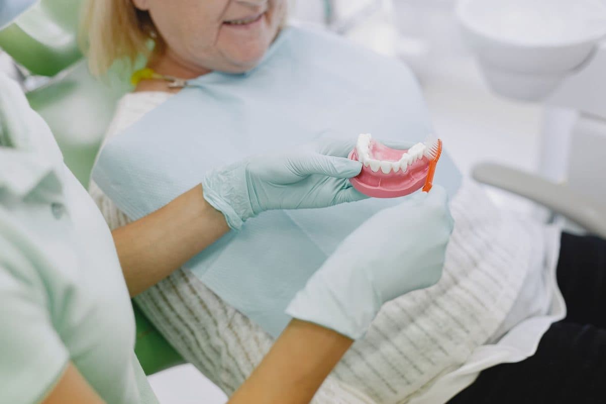 Proteză pe implanturi în Bacău: medicul îi arată pacientei cum se curăță proteza, la Chromatic Dental Clinic