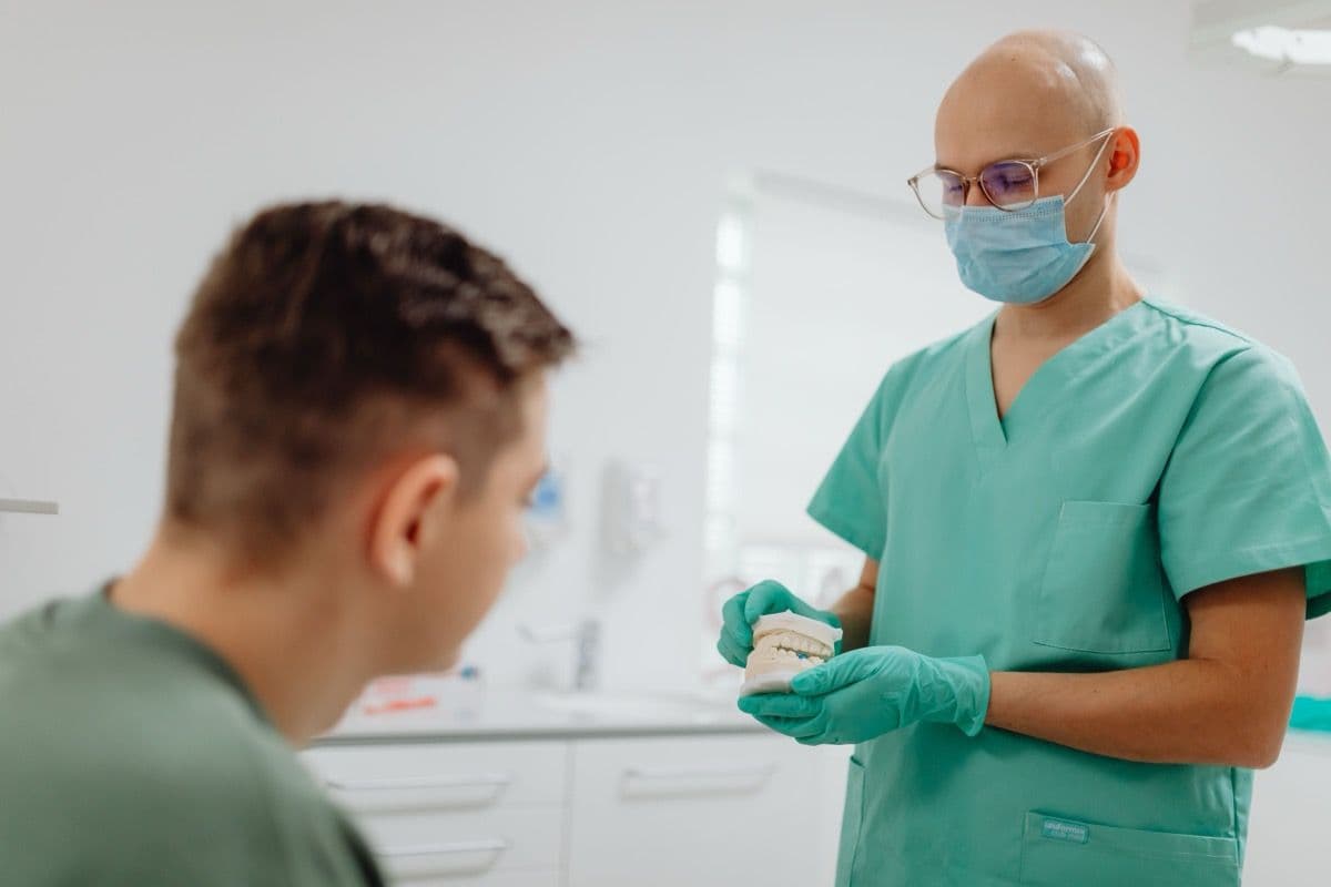 Medic explicând unui pacient, pe model, recuperarea după sinus lifting în Bacău
