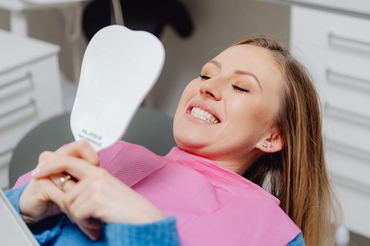 Pacientă verificând în oglindă rezultatul după fațete dentare în Bacău